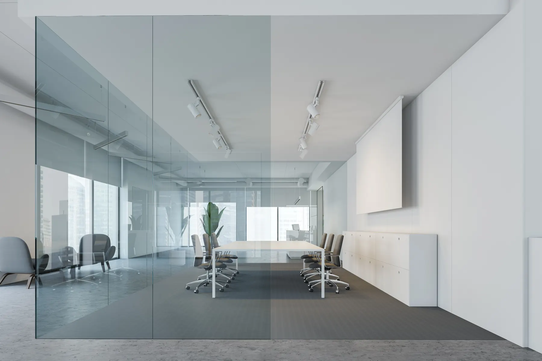 An empty meeting room behind a full height glass partition, with a blank white panel on the far wall